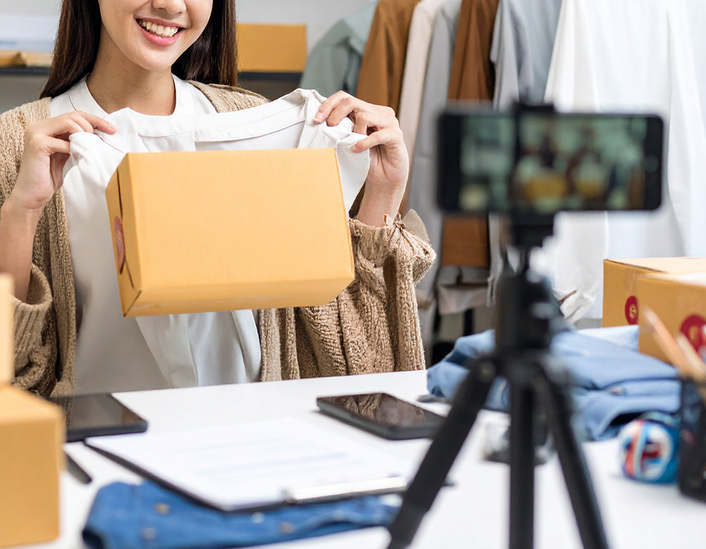 スマートフォンでライブ配信をしながら洋服を販売する女性。