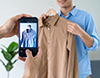 スマートフォンでハンガーにかかった洋服を撮影する様子。
