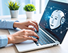 ノートパソコンに表示された笑顔のロボットアイコンを操作する人物。