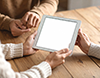 木製のテーブルでタブレットを一緒に見る二人。