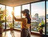 都市の夕焼けが見える部屋でVRゴーグルを装着する女性。