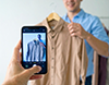 スマートフォンで洋服を撮影する男性。